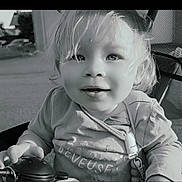 Zélia a rejoint le concours — aidez-le/la à gagner de superbes lots ! baby, black_and_white, child, closeup, clothing, curly_hair, cute, expression, face, hair, hand, infant, outdoor, portrait, seat, smile, stroller, sunlight, toddler, toy