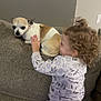 animal, brown, child, comfort, couch, cozy, curly_hair, cute, dog, gray, hand, home, indoor, interaction, pajamas, pet, relaxed, small_dog, toddler, white