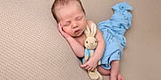 Leon is registered to the contest to win money with this photo: newborn, baby, sleeping, plush_toy, bunny, blanket, blue_blanket, couch, soft_texture, peaceful, infant, child, resting, cute, toddler, wrapped, cozy, portrait, indoor, human