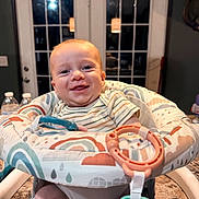 Bowen is registered to the contest to win money with this photo: baby, bouncer, countertop, cute, door, face, happy, high_chair, home, indoor, infant, kitchen, pendant_light, portrait, smiling, striped_shirt, teething, toy_ring, water_bottle, window
