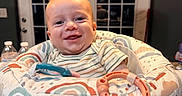 Bowen is registered to the contest to win money with this photo: baby, bouncer, countertop, cute, door, face, happy, high_chair, home, indoor, infant, kitchen, pendant_light, portrait, smiling, striped_shirt, teething, toy_ring, water_bottle, window