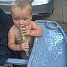 baby, bare_chested, blond_hair, car, child, cucumber, driveway, eating, food, hands, high_chair, infant, license_plate, outdoor, parked_car, portrait, side_eye, sitting, snack, toddler