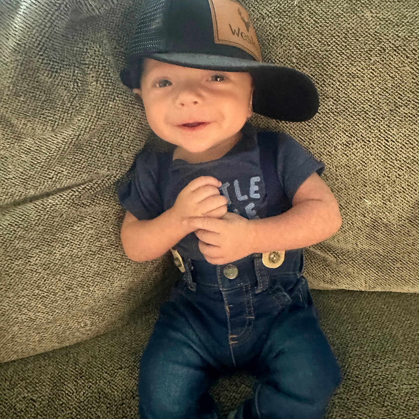 Wesley is registered to the contest to win money with this photo: baby, cap, casual, child, clothing, couch, cute, denim, face, happy, hat, indoor, infant, overalls, person, portrait, sitting, smiling, textile, young