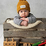 Giovanni joined the competition — help win amazing prizes! child, baby, infant, wool_hat, pom_pom, knitted_blanket, wooden_crate, toy_hammer, wooden_blocks, toy_tools, sweater, blue_eyes, serious_expression, rustic, cozy, studio_photography, portrait, floorboards, pale_background, wooden_toys