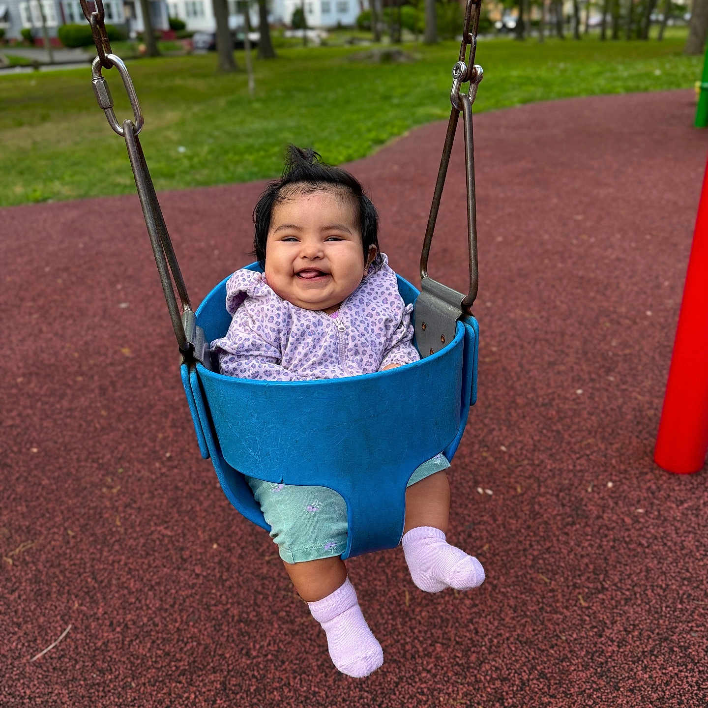 Anya is registered to the contest to win money with this photo: baby, child, swing, playground, smiling, happy, outdoor, park, grass, trees, clothing, jacket, pants, socks, person, seat, metal_chains, daylight, fun, cute
