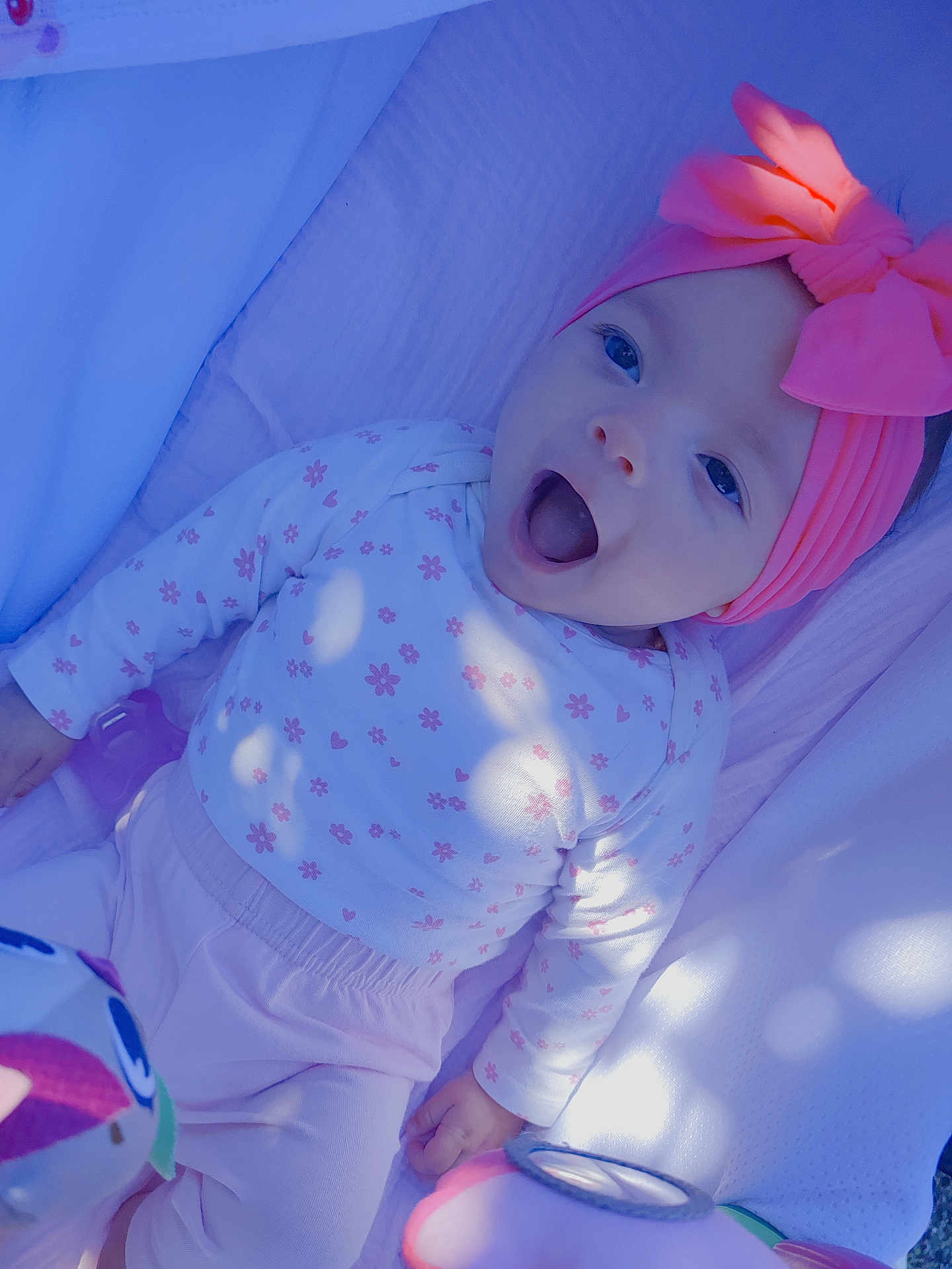 Marly participe au concours pour gagner de l'argent avec cette photo : baby, child, infant, headband, pink, bow, blanket, toy, clothing, long_sleeve, patterned, happy, smiling, lying_down, portrait, cute, indoors, soft_light, closeup, person