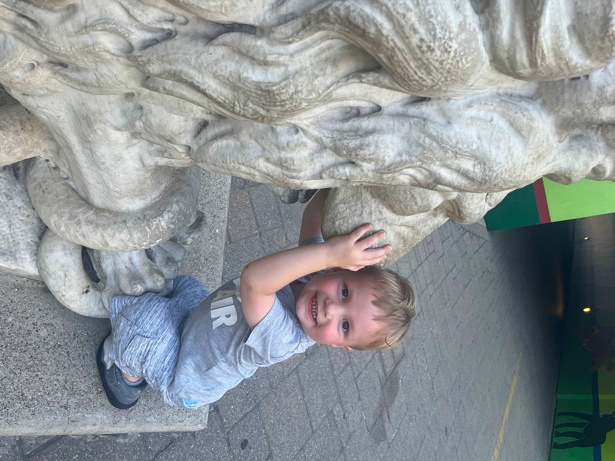 Carter is registered to the contest to win money with this photo: cement, child, concrete, denim, foot, fun, gesture, grass, grey, joy, leisure, organ, pattern, person, plant, rock, smile, t_shirt, toddler, tree