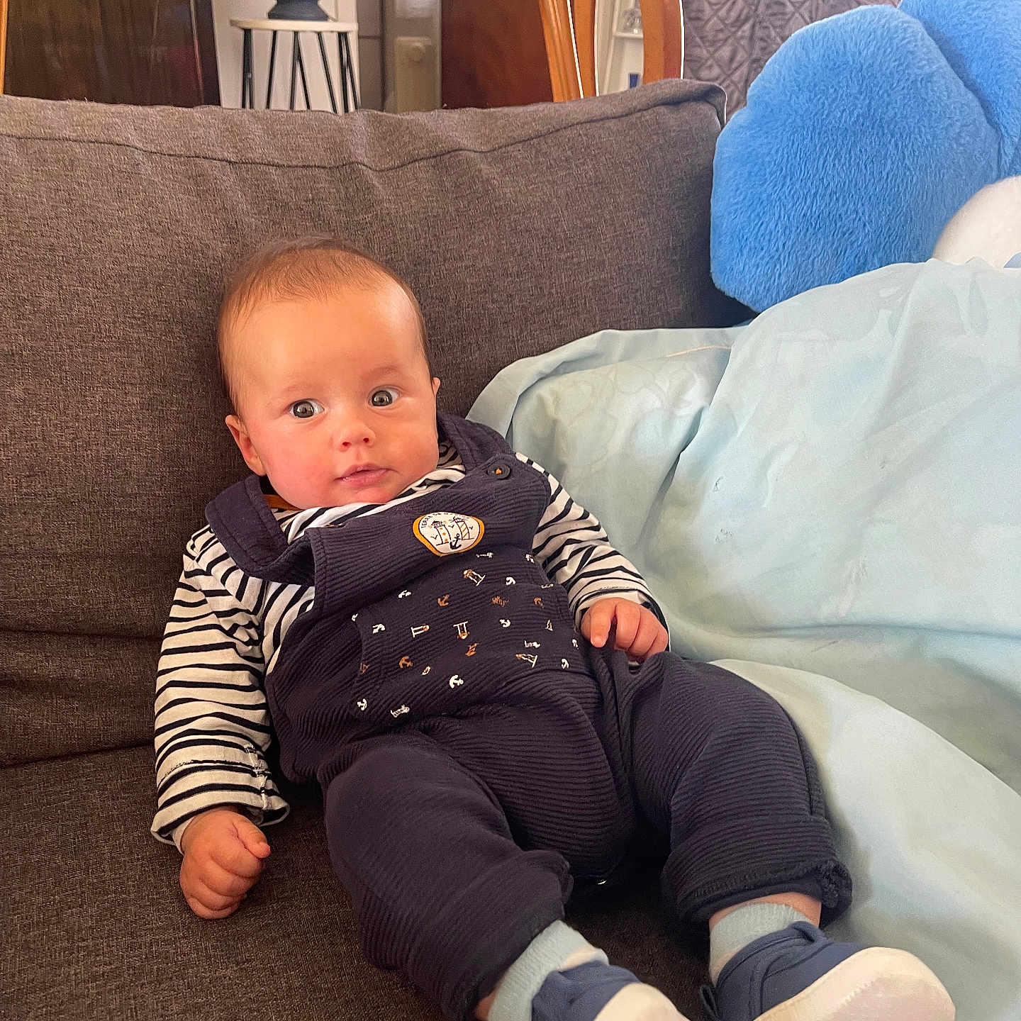 Elio participe au concours pour gagner de l'argent avec cette photo : baby, blue_shoes, casual_clothing, child, comfortable, couch, cozy, curious, expression, furniture, home_interior, indoor, infant, lamp, overalls, person, plush, seated, soft_lighting, striped_shirt