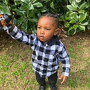 Harlem joined the competition — help win amazing prizes! child, toddler, boy, outdoor, grass, leaves, toy, toy_truck, black_and_white_clothing, plaid_shirt, braided_hair, footwear, black_pants, nature, daylight, curious_expression, standing, person, greenery, casual_wear