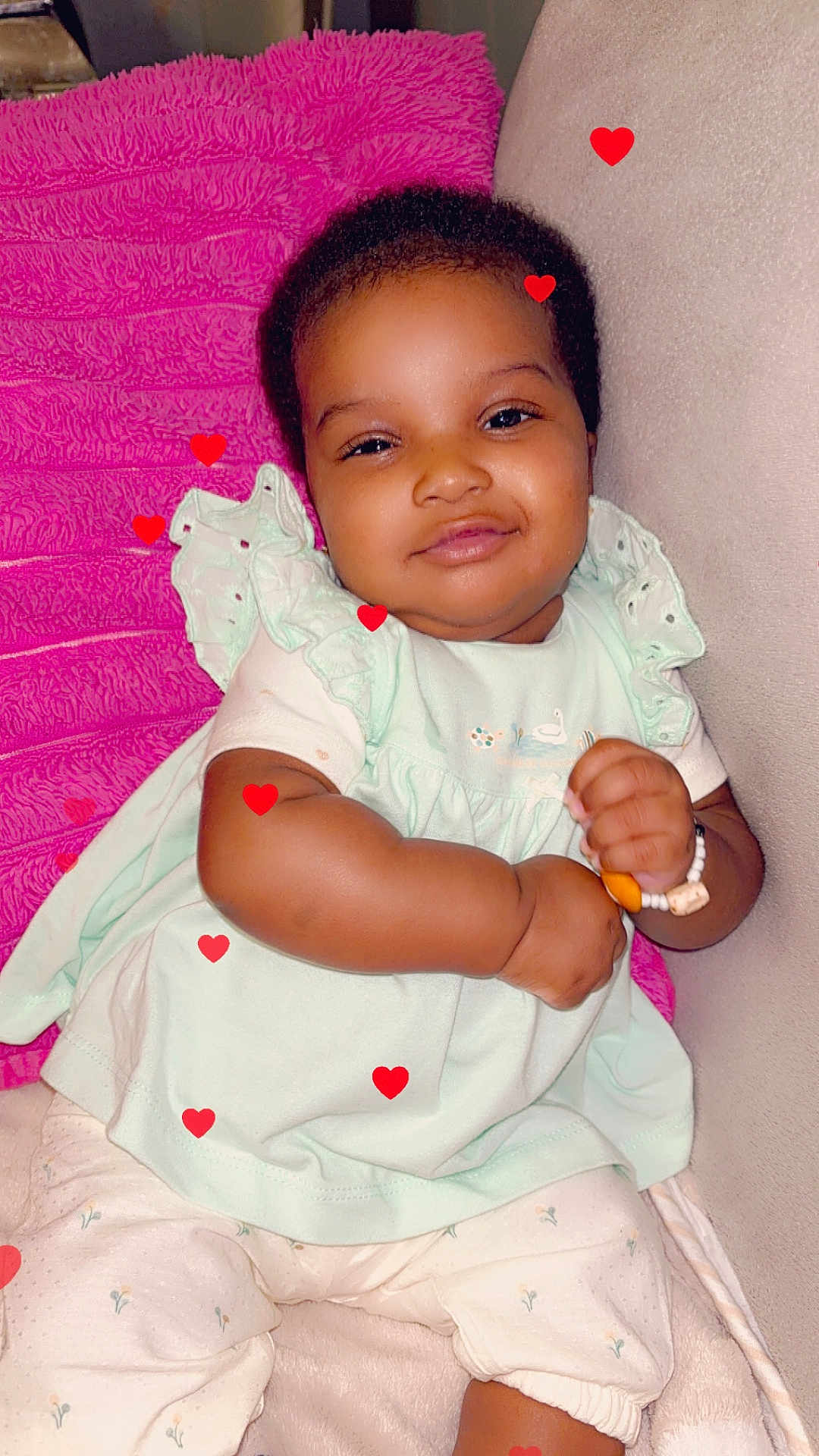 Kany a rejoint le concours — aidez-le/la à gagner de superbes lots ! baby, child, infant, smiling, sitting, bracelet, couch, pillow, pink, mint_green, clothing, cute, happy, face, indoors, plush, comfort, heart_graphics, soft, relaxed