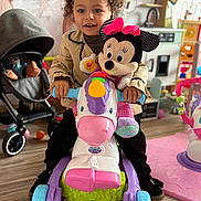 Khalessi a rejoint le concours — aidez-le/la à gagner de superbes lots ! child, clothing, colorful, curly_hair, flooring, footwear, hands, happy, headband, indoor, minnie_mouse, person, play_kitchen, playroom, plush_toy, smiling, stroller, toddler, toy, unicorn