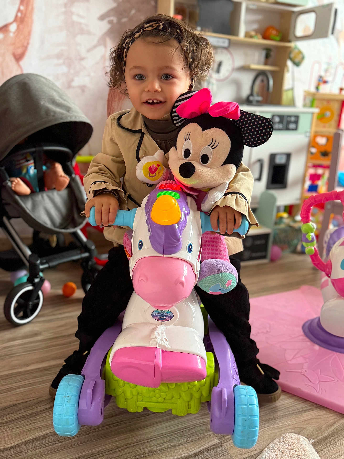 Khalessi a rejoint le concours — aidez-le/la à gagner de superbes lots ! child, clothing, colorful, curly_hair, flooring, footwear, hands, happy, headband, indoor, minnie_mouse, person, play_kitchen, playroom, plush_toy, smiling, stroller, toddler, toy, unicorn