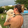 woman, puppy, dog, outdoor, grass, pool, tattoo, hair_clip, ball, playing_dog, pet, summer, back_view, greenery, animal, happy, affection, cute, garden, friendship