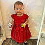 toddler, child, red_dress, gift_box, indoor, wooden_floor, black_shoes, earrings, curious, holiday, standing, person, face, young_child, lace, present, flooring, dress, fashion, portrait