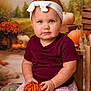 toddler, child, baby, pumpkin, headband, blue_eyes, maroon_shirt, floral_skirt, wooden_chair, autumn, fall, decor, orange, background, portrait, indoor, cute, seasonal, holiday, serious