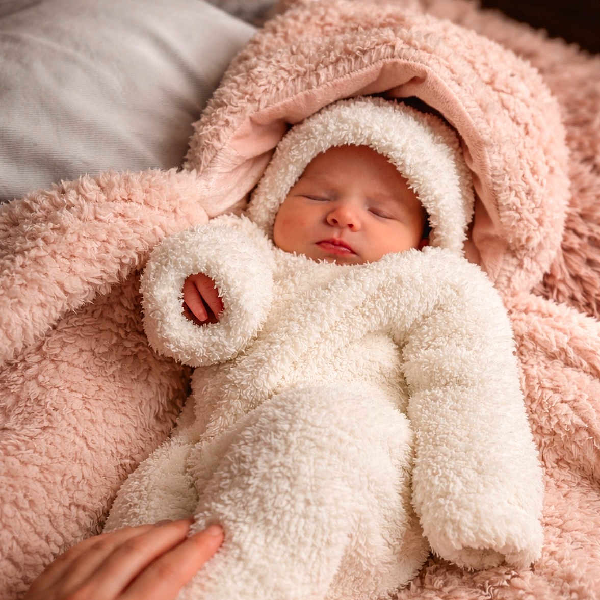 Anouk a rejoint le concours — aidez-le/la à gagner de superbes lots ! baby, sleeping, infant, onesie, fluffy_clothing, blanket, pink, white, hand, cozy, soft, cute, newborn, child, resting, portrait, indoor, warm, tenderness, cuddle