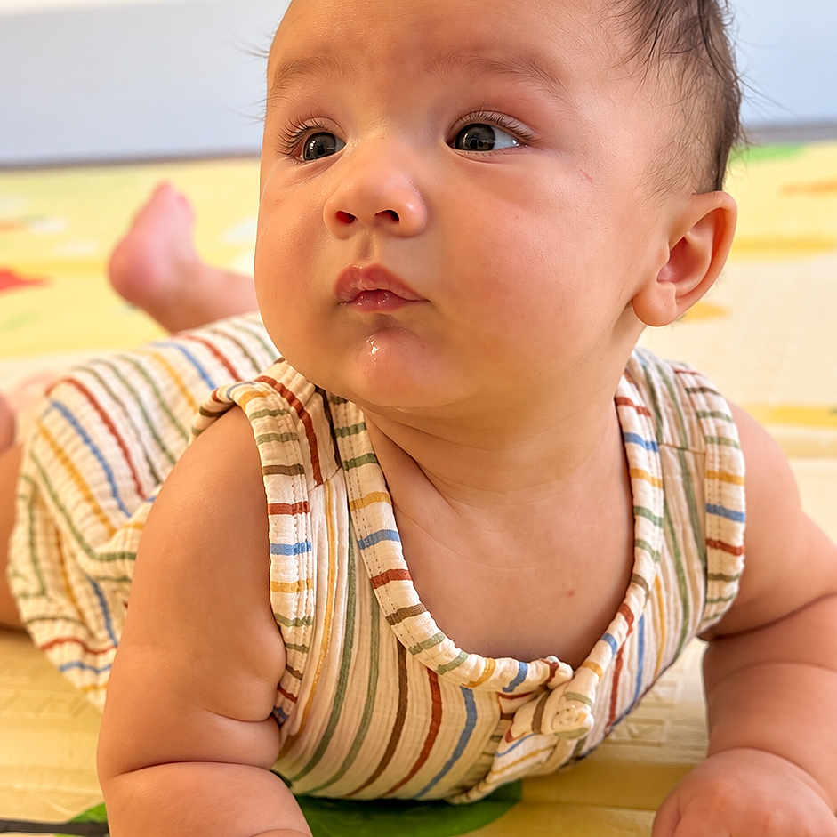 Dylan joined the competition — help win amazing prizes! baby, infant, child, tummy_time, portrait, face, eyes, hair, smiling, curious, indoor, play_mat, striped_clothing, romper, lying_down, hands, arms, colorful, close_up, photography