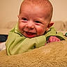 baby, infant, smiling, green_clothing, cushion, indoor, happy, face, head, child, person, lying_down, closeup, skin, cute, young, expression, comfort, soft, home