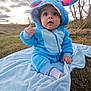 Malakai joined the competition — help win amazing prizes! baby, child, blue_onesie, blanket, outdoor, grass, sky, cloudy, cute, plush, hooded, ears, sitting, curious, young_child, nature, daylight, clothing, portrait, expression