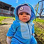 toddler, child, blue_onesie, purple_hat, daisy_patch, outdoor, grass, sky, clouds, porch, sidewalk, gloves, winter_clothing, playground, swing, trees, sunny, face, curious, seated