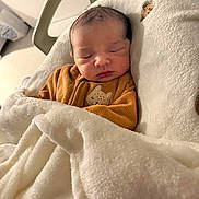 Naël participe au concours pour gagner de l'argent avec cette photo : newborn, baby, sleeping, blanket, brown_clothing, face, indoor, cozy, soft_lighting, infant, cute, child, wrapped, peaceful, resting, furniture, head, warm, portrait, toddler