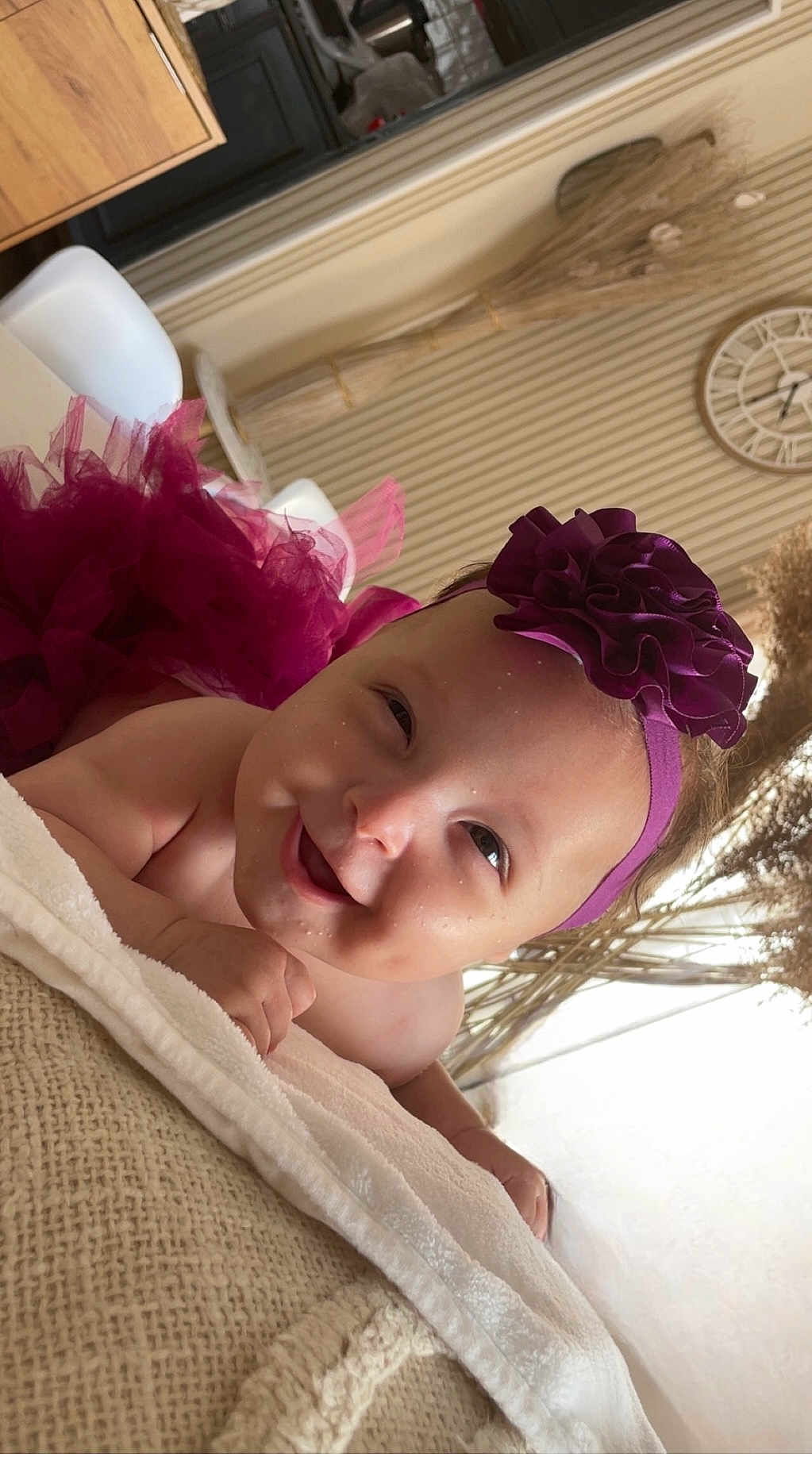 Zaïna participe au concours pour gagner de l'argent avec cette photo : baby, headband, flower, smile, dimple, blanket, indoor, decor, clock, happy, child, infant, person, portrait, skin, tulle, fabric, couch, hand, lying