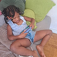 Rosestrella a rejoint le concours — aidez-le/la à gagner de superbes lots ! child, girl, couch, pillows, blanket, floor, wood_floor, device, handheld, screen, indoors, casual_clothing, denim_shorts, striped_top, braids, beads, relaxing, playing, barefoot, home