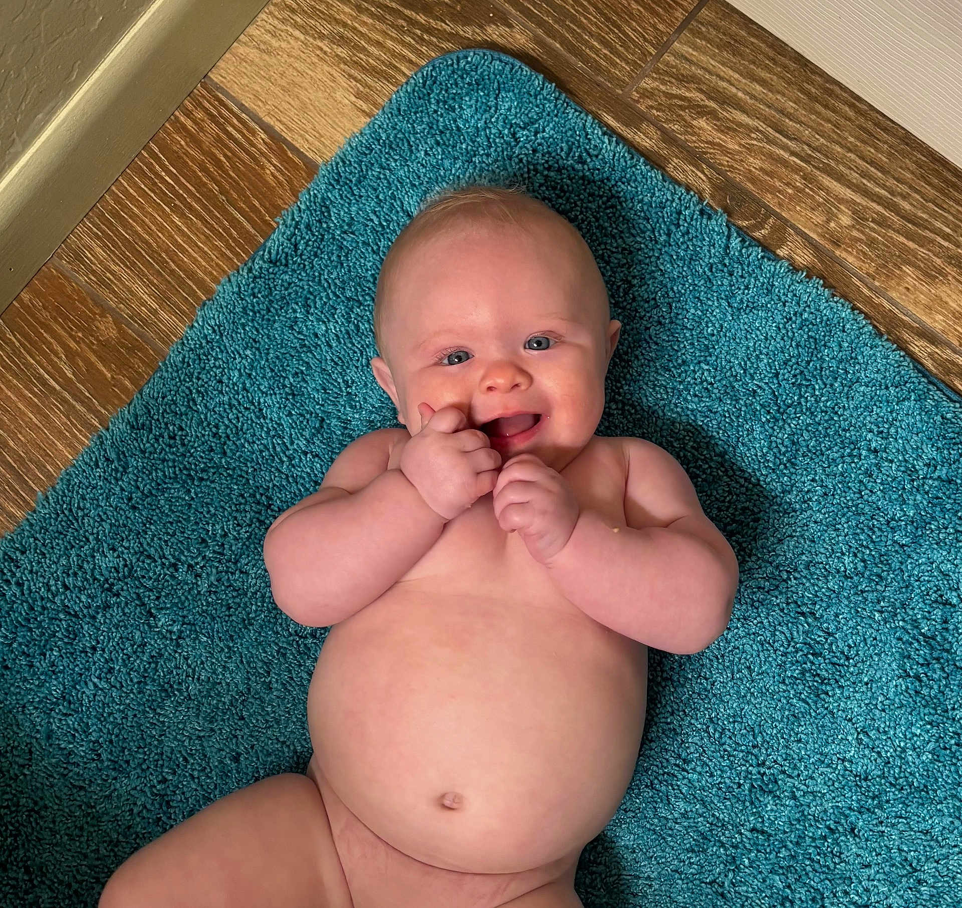 Creed Taylor is registered to the contest to win money with this photo: baby, child, infant, smiling, happy, naked, blue_rug, floor, wooden_floor, skin, cute, chubby, hands, face, eyes, mouth, lying_down, indoors, playful, person