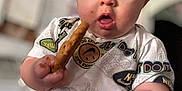 Creed Taylor is registered to the contest to win money with this photo: baby, blue_eyes, blurred_background, child, chubby_cheeks, cookie, curious, cute, food, hand, home, indoor, infant, messy_face, mouth_open, person, shorts, sitting, snack, tshirt