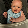 baby, child, high_chair, bib, blue_eyes, smile, whale_pattern, cute, infant, chubby_cheeks, feeding, happy, clothing, face, hand, indoor, person, portrait, skin, seat