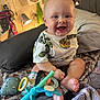 baby, bed, blanket, child, clothing, cute, decor, face, foot, hand, happy, indoor, infant, lamp, person, pillow, room, sitting, smiling, toy