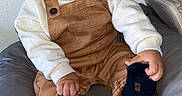 Elaïjah participe au concours pour gagner de l'argent avec cette photo : baby, child, clothing, couch, cushion, face, footwear, hand, happy, head, indoors, infant, overalls, person, portrait, sitting, skin, smiling, sock, sweater