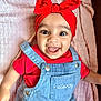 baby, cherry_pattern, child, closeup, clothing, cute, denim_overalls, face, happy, headwear, hello_kitty, human, indoor, infant, joyful, pink_blanket, portrait, red_headband, smiling, toddler
