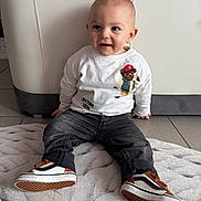 Hayden a rejoint le concours — aidez-le/la à gagner de superbes lots ! toddler, child, sitting, shirt, jeans, sneakers, rug, couch, floor, indoor, smile, happy, baby, clothing, footwear, person, cute, casual, portrait, home