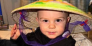 Hayden participe au concours pour gagner de l'argent avec cette photo : toddler, child, hat, conical_hat, purple_ribbon, black_jacket, carpet, indoor, person, face, eyes, hand, floor, pattern, curious, cute, smiling, baby, young_child, home