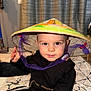 toddler, child, hat, conical_hat, purple_ribbon, black_jacket, carpet, indoor, person, face, eyes, hand, floor, pattern, curious, cute, smiling, baby, young_child, home
