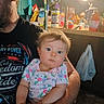 River joined the competition — help win amazing prizes! baby, child, adult, person, arm, clothing, tshirt, face, hair, indoor, kitchen, light, bottle, container, plastic_bag, counter, food, expression, holding, portrait
