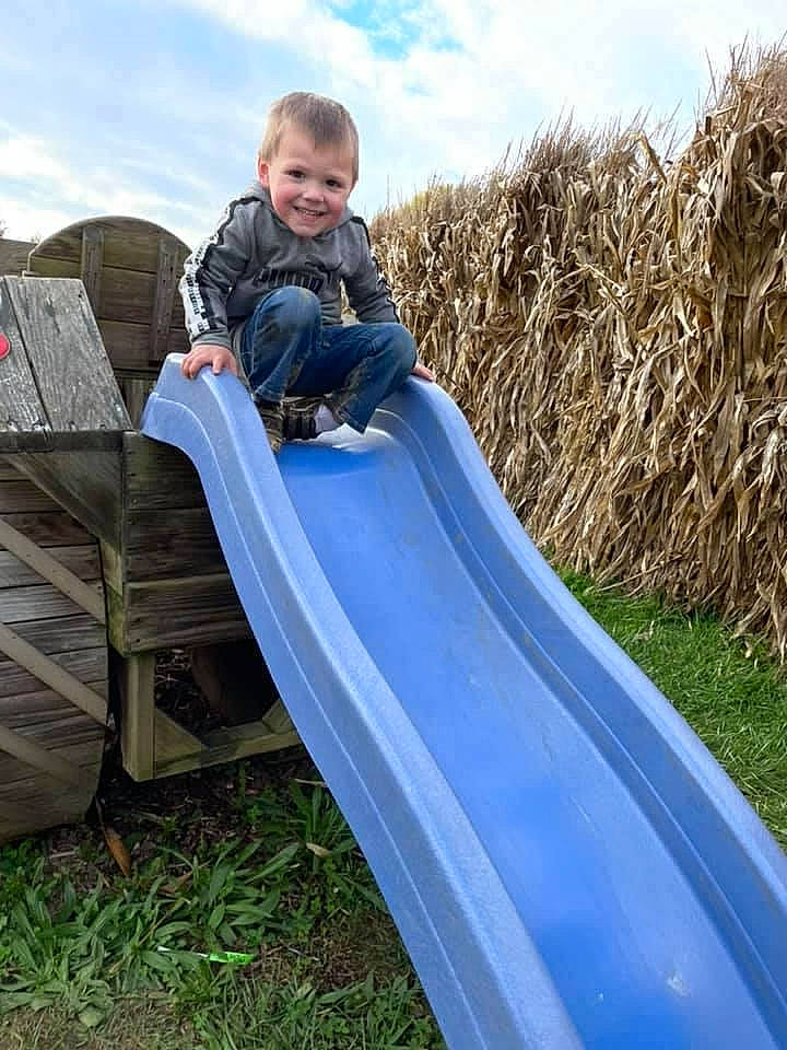 Brantlei is registered to the contest to win money with this photo: chute, cloud, fun, grass, grassland, happy, joy, leisure, natural_environment, outdoor_play_equipment, people, people_in_nature, person, plant, playground, playground_slide, recreation, sky, smile, toddler