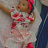 Skylah is registered to the contest to win money with this photo: baby, infant, child, headband, pink, floral_dress, striped_skirt, socks, blanket, bed, sleepwear, laying_down, cute, indoors, portrait, looking_away, soft_lighting, home, person, young