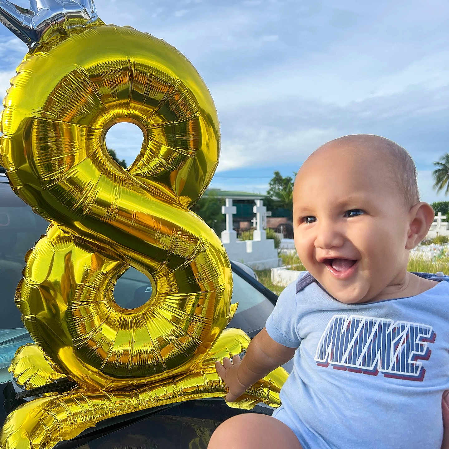 Iavaiatea participe au concours pour gagner de l'argent avec cette photo : baby, smiling, balloon, number_8, golden_balloon, crown_balloon, blue_sky, outdoor, onesie, happy, child, portrait, hand, grass, cross, cemetery, reflection, car, person, celebration