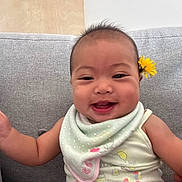 Erzabelle is registered to the contest to win money with this photo: baby, smiling, flower, bib, couch, indoors, child, happy, cute, sitting, infant, clothing, portrait, face, head, skin, young, playful, yellow_flower, home