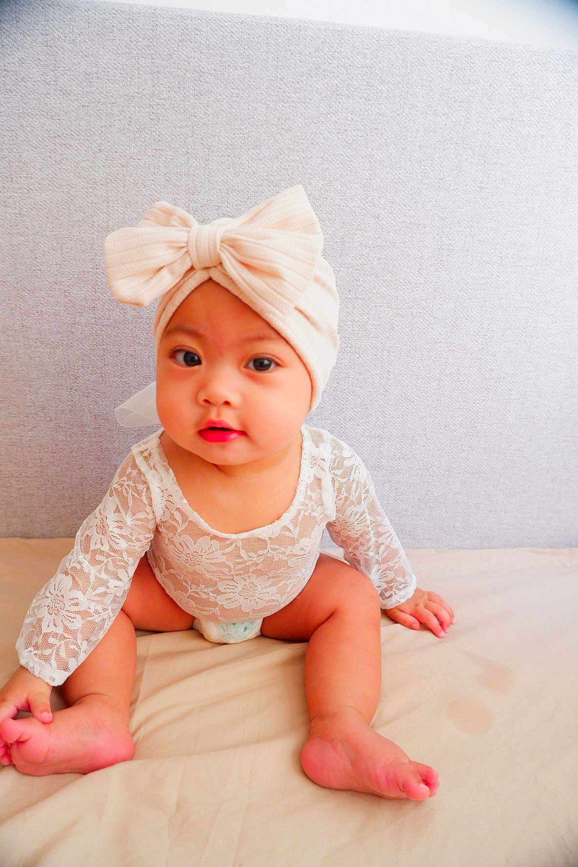Erzabelle is registered to the contest to win money with this photo: baby, child, infant, sitting, lace_outfit, headband, bow, cute, indoors, portrait, skin, face, eyes, hands, feet, soft_lighting, fabric, bed, curious, young