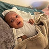 baby, bed, blanket, child, comfort, cozy, cute, face, happy, indoors, infant, lying_down, peaceful, pillow, portrait, relaxation, smile, soft_texture, warm_lighting, white_clothing