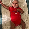 Sekai is registered to the contest to win money with this photo: baby, blanket, child, comfort, cute, expression, fabric, face, foot, hand, indoors, infant, lying_down, onesie, pattern, person, raised_arm, red_clothing, skin, tongue_out