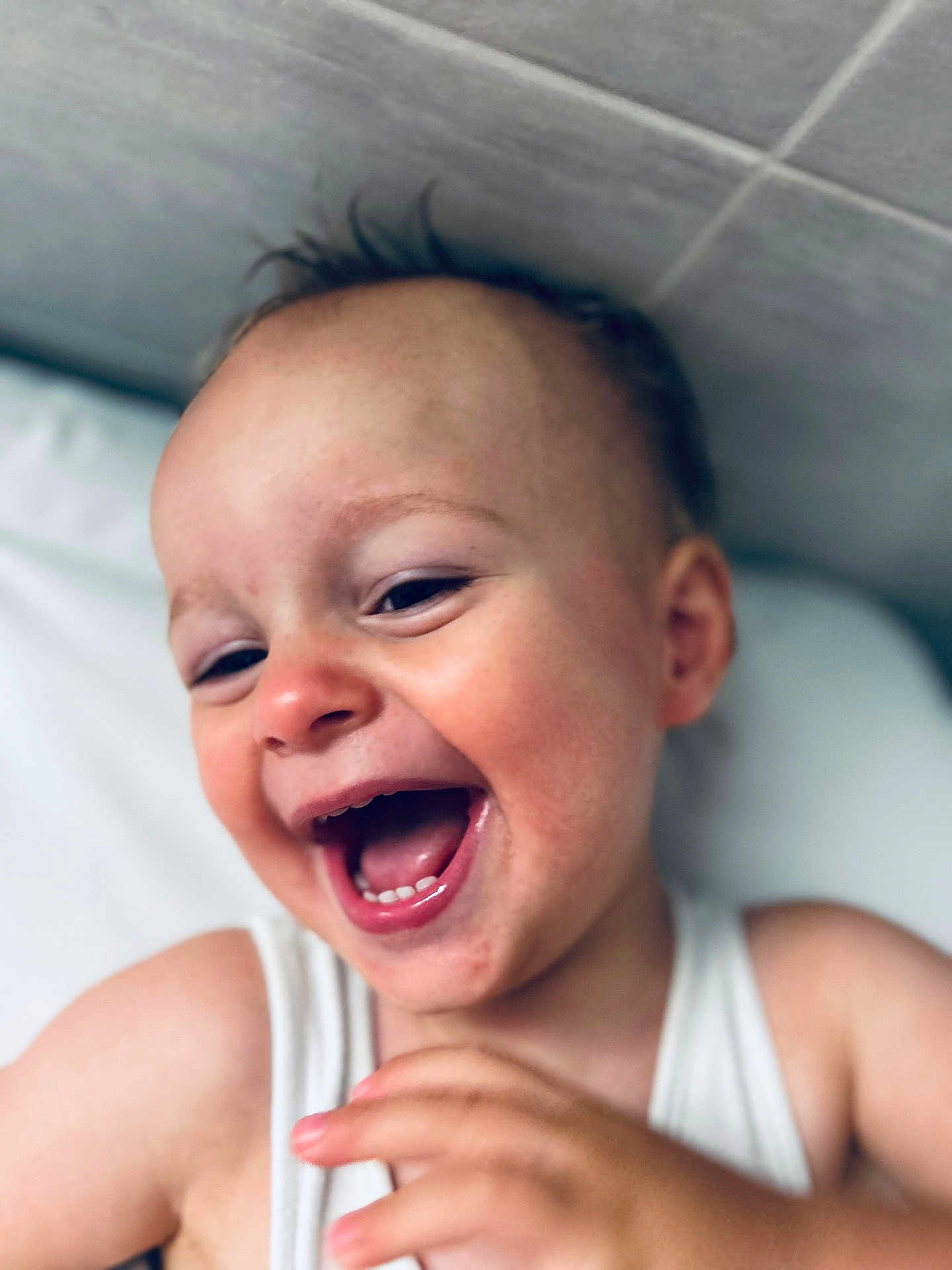Roman participe au concours pour gagner de l'argent avec cette photo : toddler, child, smiling, laughing, face, closeup, happy, skin, hand, white_shirt, indoors, pillow, head, expression, joy, person, cute, baby, portrait, light