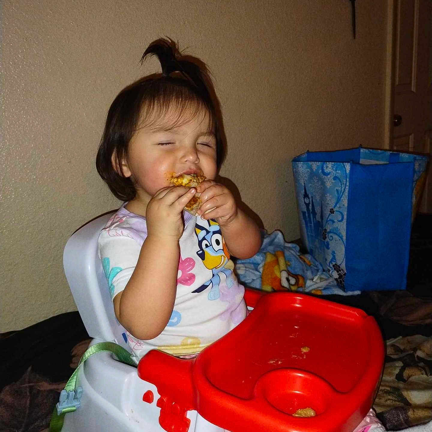 Mira is registered to the contest to win money with this photo: baby, biting, bread, clothing, couch, cutlery, eating, face, food, furniture, head, indoors, ketchup, lunch, person, photography, pizza, portrait, spoon, t_shirt