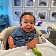 Levi joined the competition — help win amazing prizes! baby, high_chair, smiling, curly_hair, food, green_food, lime, face, child, indoor, furniture, person, happy, shirt, table, home, photography, portrait, infant, cute