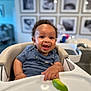 baby, high_chair, smiling, curly_hair, food, green_food, lime, face, child, indoor, furniture, person, happy, shirt, table, home, photography, portrait, infant, cute