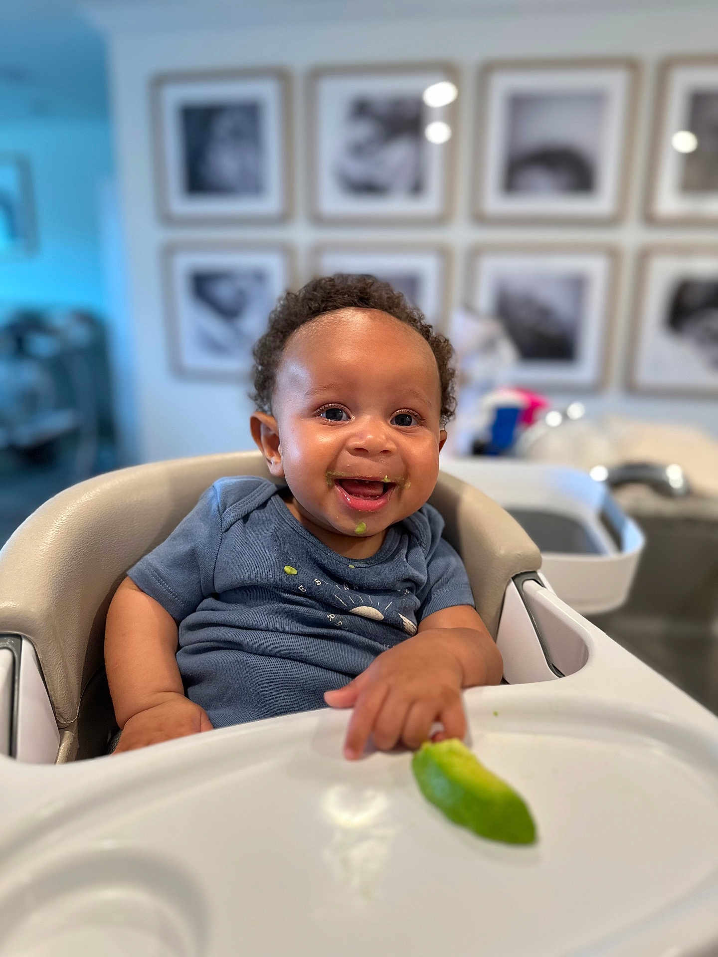 Levi joined the competition — help win amazing prizes! baby, high_chair, smiling, curly_hair, food, green_food, lime, face, child, indoor, furniture, person, happy, shirt, table, home, photography, portrait, infant, cute