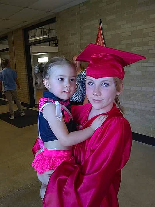 Jarrette is registered to the contest to win money with this photo: academic_dress, clothing, costume, event, graduation, headgear, headwear, interaction, magenta, mortarboard, person, phd, pink, smile